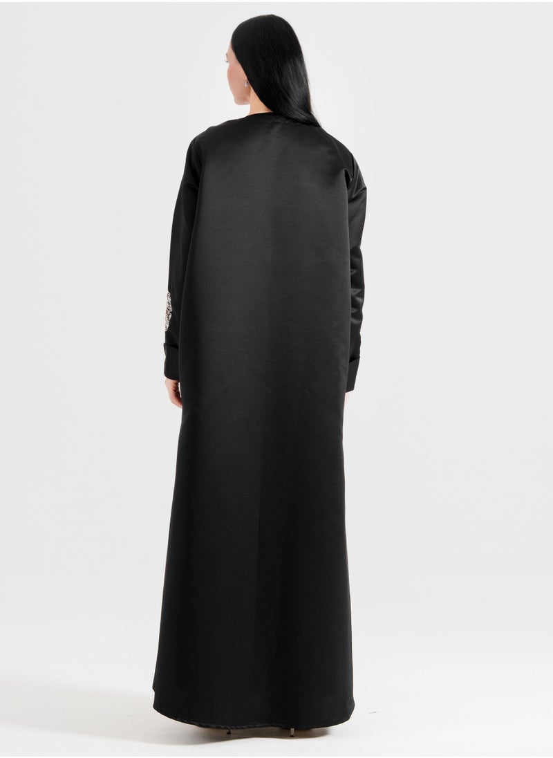 A luxurious abaya featuring silver Arabic-inspired hand embroidery